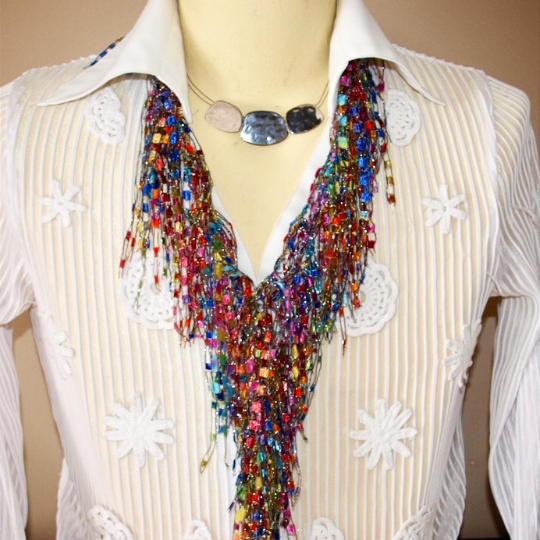 Multistrand jewelry necklace scarf on a mannequin and behind the collar of a white blouse 